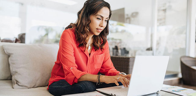 Woman-in-red-shirt-using-laptop-on-couch