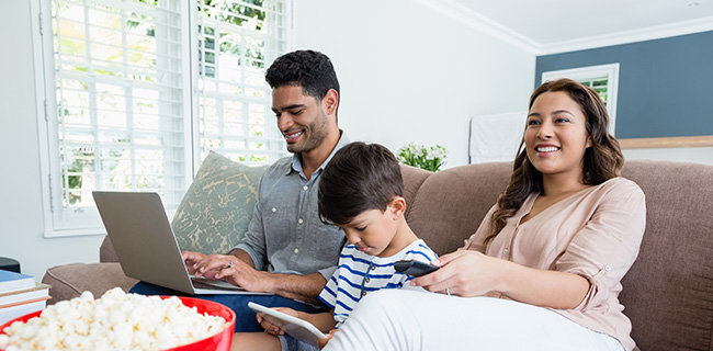 Family using internet sitting on couch